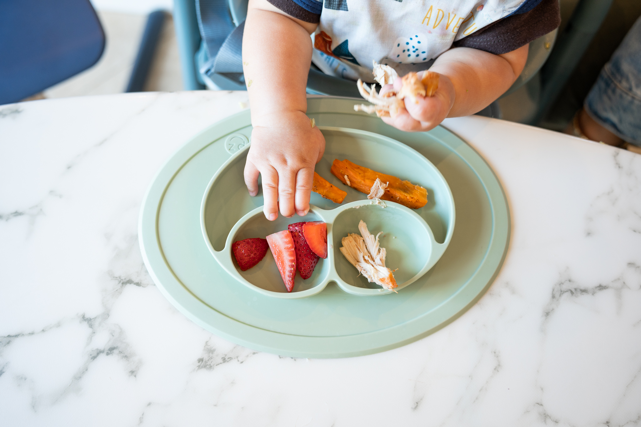 Baby self-feeding with strawberries and sweet potato